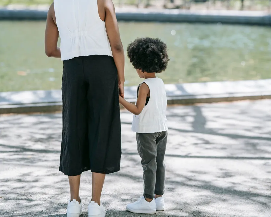 A woman and a young child walking hand in hand