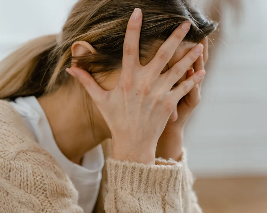 A woman sitting with her head in her hands, feeling overwhelmed
